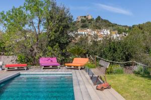 a swimming pool with colorful chairs next to a house at Flateli Begur Cabanya in Begur