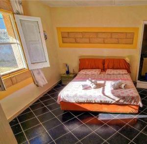 シラクーサにあるVillino Relaxのベッドルーム1室(オレンジ色のベッド1台、タオル付)