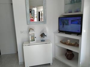 een woonkamer met een tv en een witte kast bij Little Paradise . Apartment in front of the sea in Comarruga