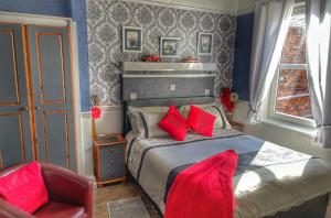 a bedroom with a bed with red pillows and a chair at Atlanta Hotel in Scarborough