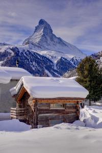 ツェルマットにあるChalet Alpoaseの山を背景にした雪の丸太小屋
