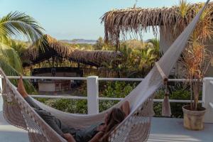a woman laying in a hammock on a balcony at Casas Kismet in Nosara