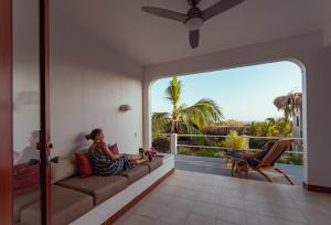 a woman sitting on a couch on the porch of a house at Casas Kismet in Nosara