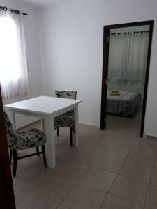 una mesa y sillas blancas en una habitación con espejo en RCM Vilas - STUDIO n 05, en Joinville