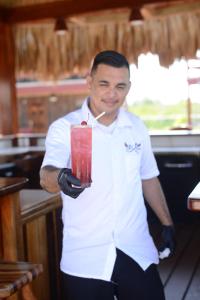 a man in a kitchen holding a red drink at El Ben Cabañas in Caye Caulker