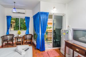 a living room with blue curtains and a television at Sutus Court 2 in Pattaya Central