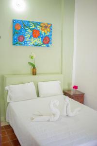 een slaapkamer met een wit bed met een foto aan de muur bij Hotel Posada San Jose in San Pedro Pochutla
