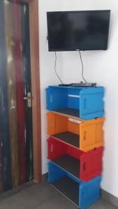 a tv on a wall with colorful drawers at Casa do Ipê - Hospedagem in Lumiar