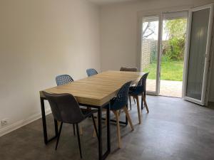 comedor con mesa de madera y sillas en Maison joliment rénovée à 5 minutes du futuroscope, en Chasseneuil-du-Poitou