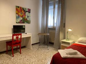 a bedroom with a desk and a bed with a red chair at Affittacamere Room ospedale Maggiore in Parma