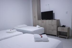 a hotel room with three beds and a flat screen tv at OMA HOTEL LA GUAJIRA in Camarones