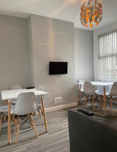 uma sala de estar com mesas e cadeiras e uma televisão em Modern House In Stoke on Trent em Stoke on Trent