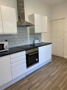 a kitchen with white cabinets and a stove top oven at Modern House In Stoke on Trent in Stoke on Trent