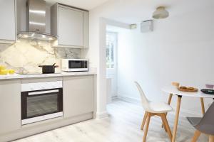 a kitchen with white cabinets and a table and a microwave at Stylish, spacious flat with private parking in Bristol