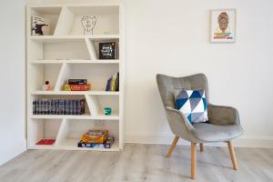 a chair with a pillow sitting in front of a book shelf at Stylish, spacious flat with private parking in Bristol