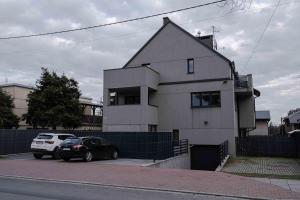 a white house with two cars parked in front of it at Katowicka Premium Apartment in Kraków