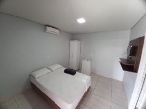 a bedroom with a white bed and a small refrigerator at Hotel Home in Lucas do Rio Verde