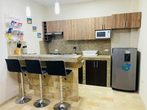 a kitchen with a refrigerator and two bar stools at NCG SUITE SAMANES in Guayaquil