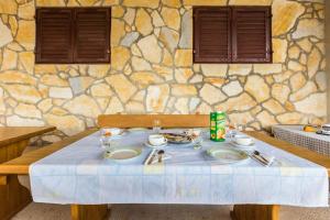 a table with plates of food on it in front of a stone wall at Picić Guesthouse in Luka