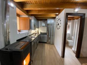 una cocina con electrodomésticos de acero inoxidable y techos de madera. en La morada del tio, en San Felices de los Gallegos