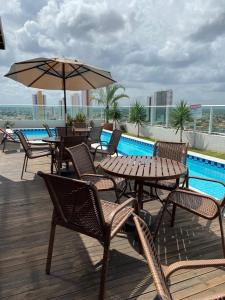 een patio met tafels en stoelen en een zwembad bij Estudio Confort West Flat com ótima localização. in Mossoró