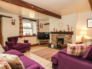 a living room with purple furniture and a fireplace at 14 Low Row in Holker