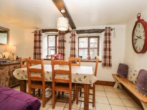 a dining room with a table and chairs and a clock at 14 Low Row in Holker