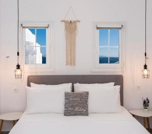 a bedroom with a bed with white pillows and two windows at Myconian Little Venice Elite Suites with Sea View in Mýkonos City