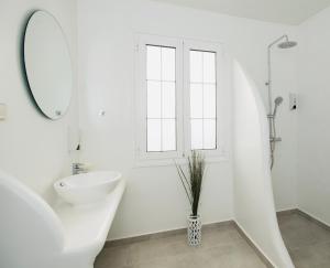 La salle de bains blanche est pourvue d'un lavabo et d'un miroir. dans l'établissement Myconian Little Venice Elite Suites with Sea View, à Mykonos