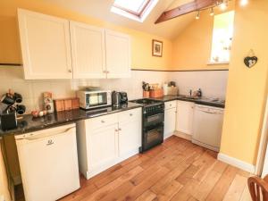 a kitchen with white cabinets and a stove top oven at Norah's Nook in Gillamoor