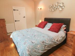 a bedroom with a large bed with red pillows at Norah's Nook in Gillamoor