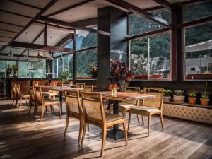 un ristorante con tavoli e sedie in legno e grandi finestre di Jaya Machu Picchu Boutique Hotel a Machu Picchu
