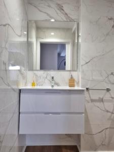 een witte badkamer met een wastafel en een spiegel bij Aujada playa in Cádiz
