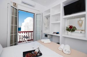 Cette chambre blanche dispose d'une grande fenêtre avec vue. dans l'établissement Myconian Little Venice Elite Suites with Sea View, à Mykonos