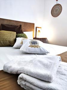 Una cama con mantas blancas y almohadas. en La Dama Boba, en Olmedo