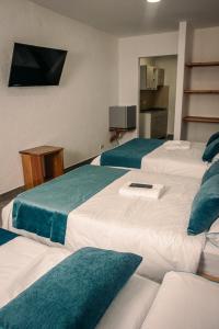 Habitación de hotel con 3 camas con almohadas verdes en Hotel Santa Laura, en Jericó
