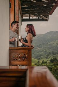 un hombre y una mujer de pie en un balcón con una taza de café en Hotel Santa Laura, en Jericó