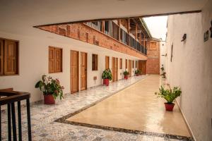 un couloir vide avec des plantes en pot dans un bâtiment dans l'établissement Hotel Santa Laura, à Jericó