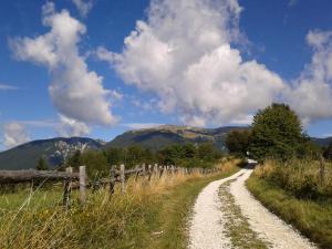 a dirt road with a fence and mountains in the background at Hotel Alpi - Foza in Foza