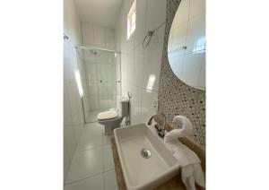 a bathroom with a sink and a toilet and a mirror at Pousada Casa da Cion in Jericoacoara