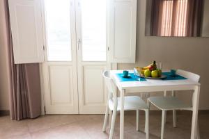 a white table and chairs with a bowl of fruit on it at Oikos - Ragusa Ibla in Ragusa