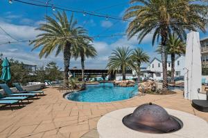 ein Pool mit Palmen und ein Gebäude in der Unterkunft Sandy Cheeks in Santa Rosa Beach