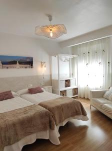 1 dormitorio blanco con 2 camas y sofá en Kaixo Salegi Piso centro 2h-Salon-2wc-Parking-ESS02940 en Zarautz