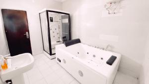 a white bathroom with a tub and a sink at Royal Court Lounge & Boutique Hotel in Port Harcourt +44 photos