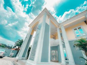 a blue and white house with columns at Royal Court Lounge & Boutique Hotel in Port Harcourt