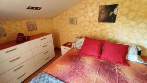 sypialnia z łóżkiem z czerwonymi poduszkami i komodą w obiekcie A Cruz de Ferro w mieście Rosal