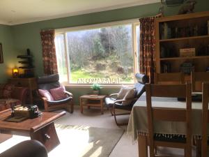 a living room with a window and chairs and a table at "An Comaraich - The Sanctuary" in Inverinate