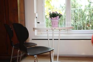 two chairs and a table with a vase of flowers on it at GoVienna - Charming Studio in Vienna