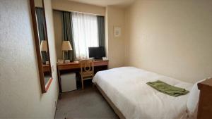 a hotel room with a bed and a desk with a computer at Ueno Terminal Hotel in Tokyo