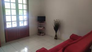 a living room with a red couch and a tv at La petite campagne in Le Moule